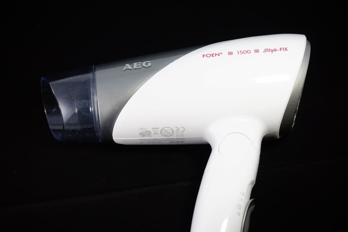 Close-up photo of a white hair dryer on a black background.