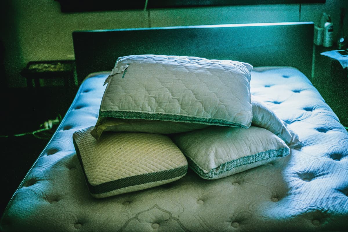 A dimly lit room with pillows piled high on the mattress.