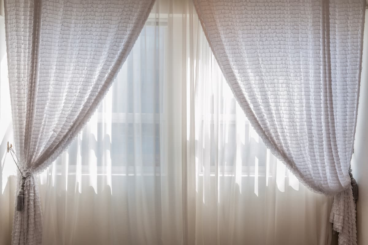 A photo of a white curtain on the window. 