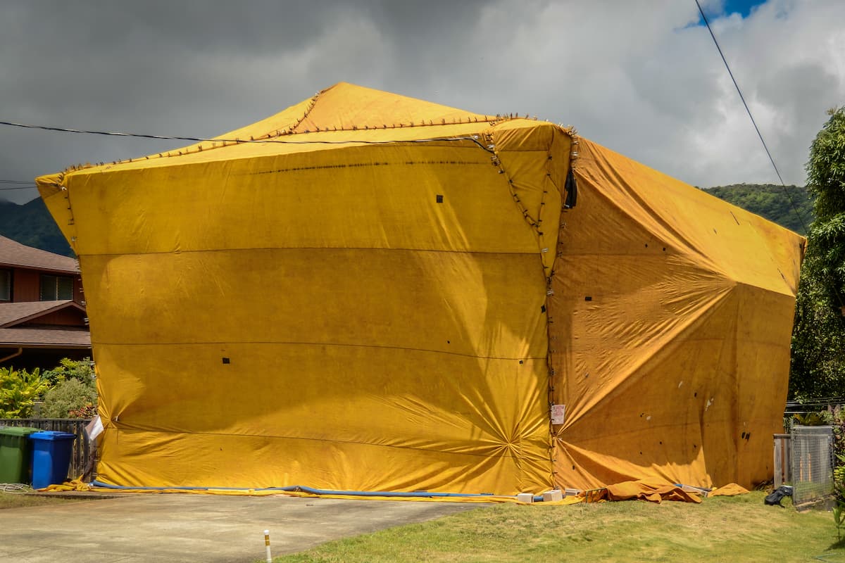 A house covered by a yellow tent to exterminate termites.