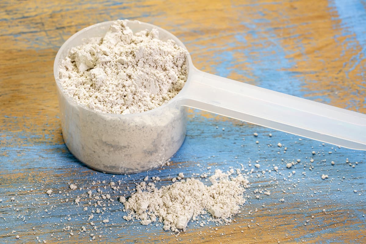 Photo of Diatomaceous earth in a plastic spoon and some on the wooden surface.