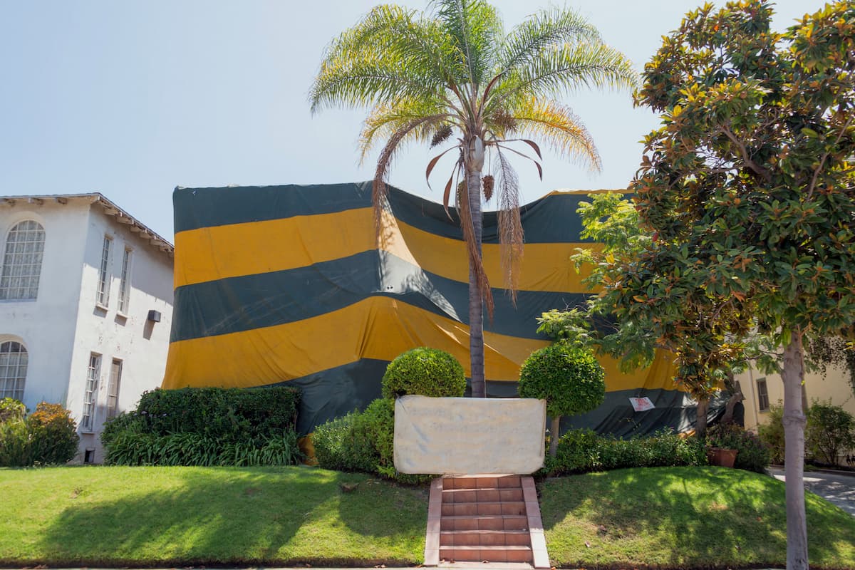 A house is covered with a yellow and gray tent to exterminate termites and other insects. 