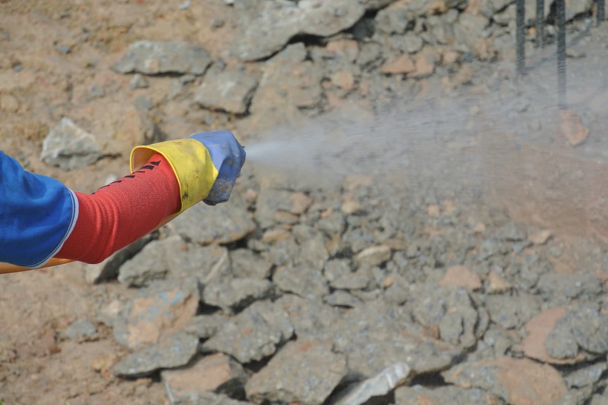 A person is spraying an anti-termite treatment on a construction site.