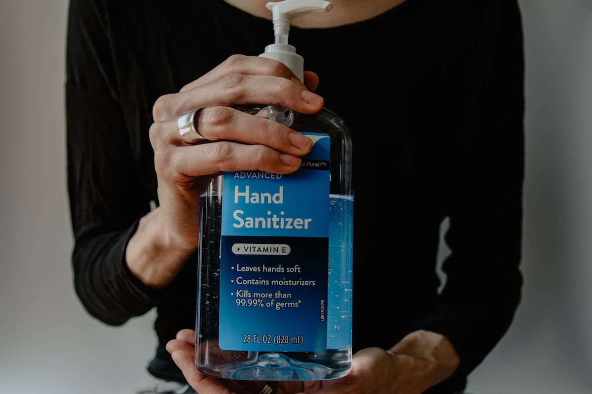A person in black long sleeves holding a hand sanitizer. 