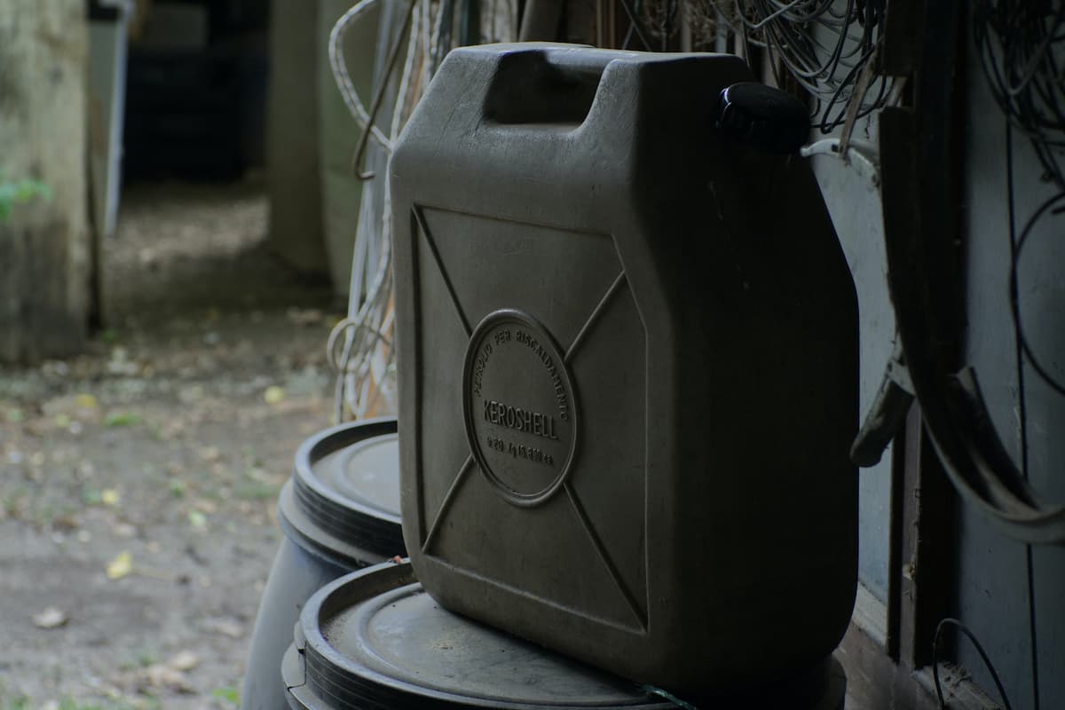 A black kerosene container on top of a black plastic barrel. 
