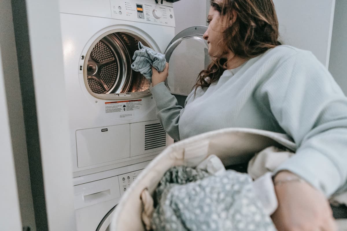 A woman loading clothes in the washing machine.