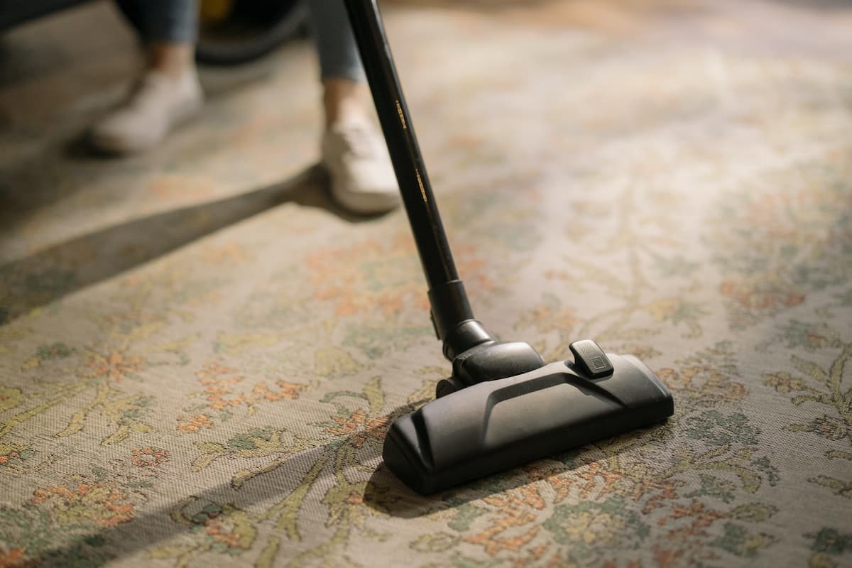 A black vacuum cleaner on a floral carpet. 