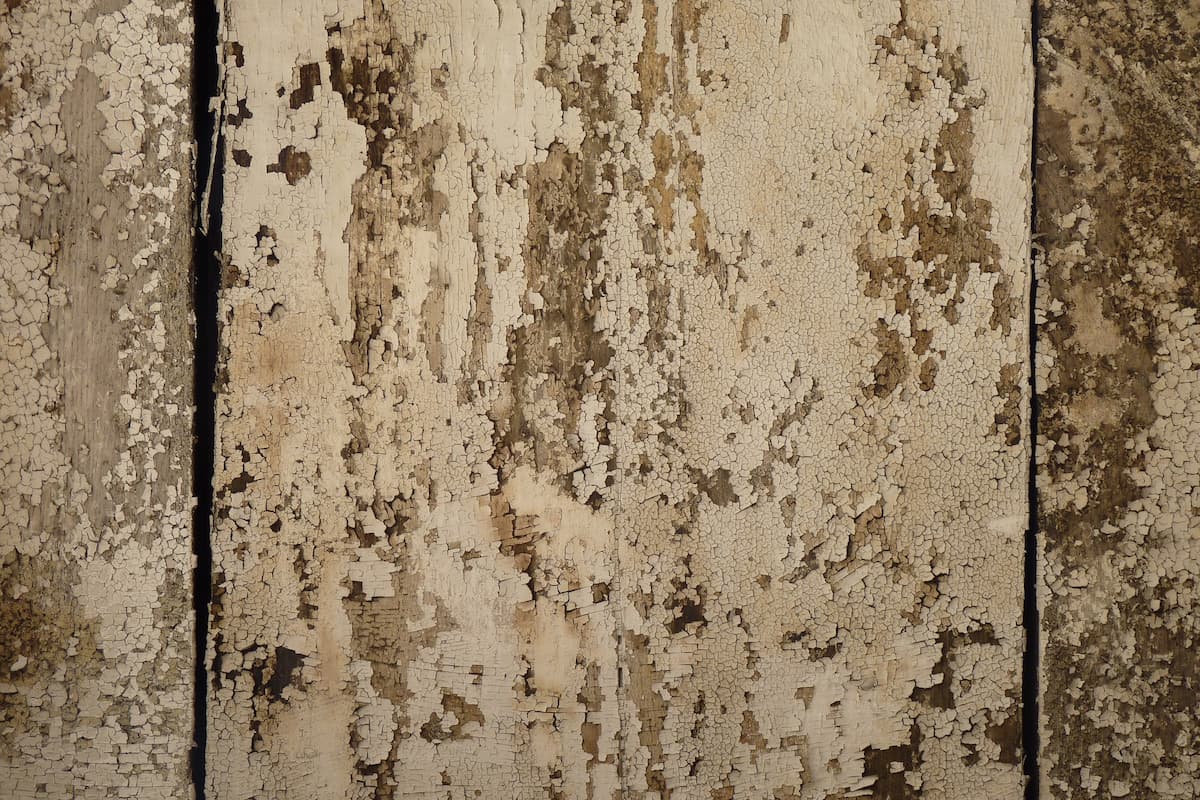 Close-up photo of a wooden wall with chipped paint and cracks. 
