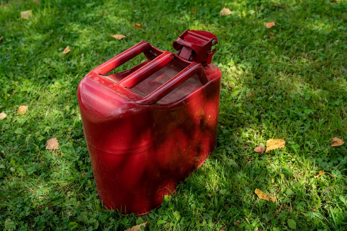 A red canister of petrol is on grass. 