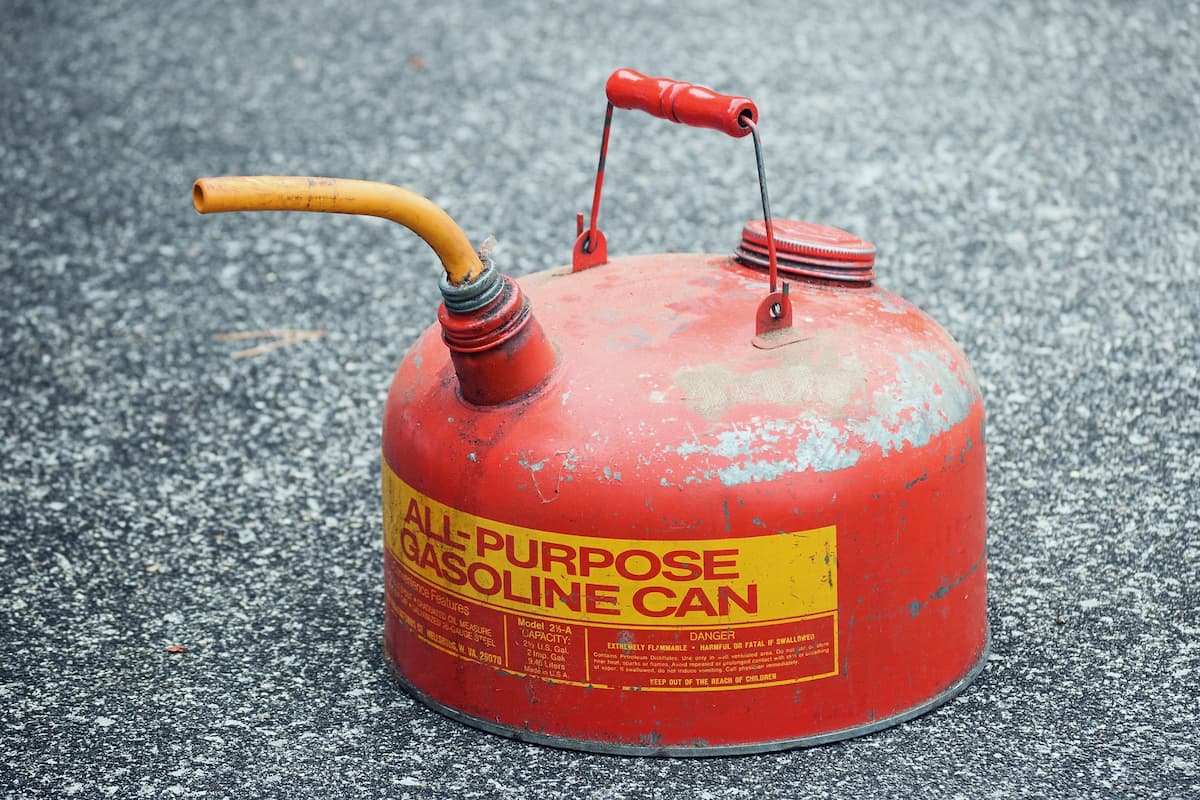 A red all-purpose gasoline can on the ground. 